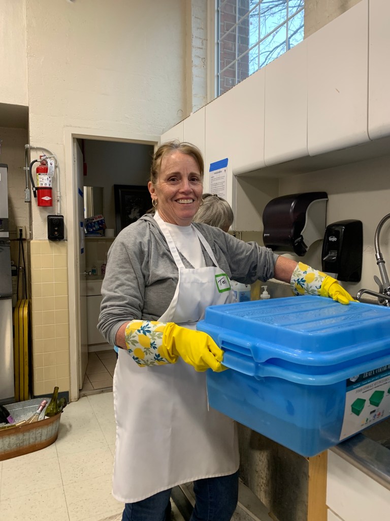 An eager volunteer washes dishes at the Saint James Fish Fry.